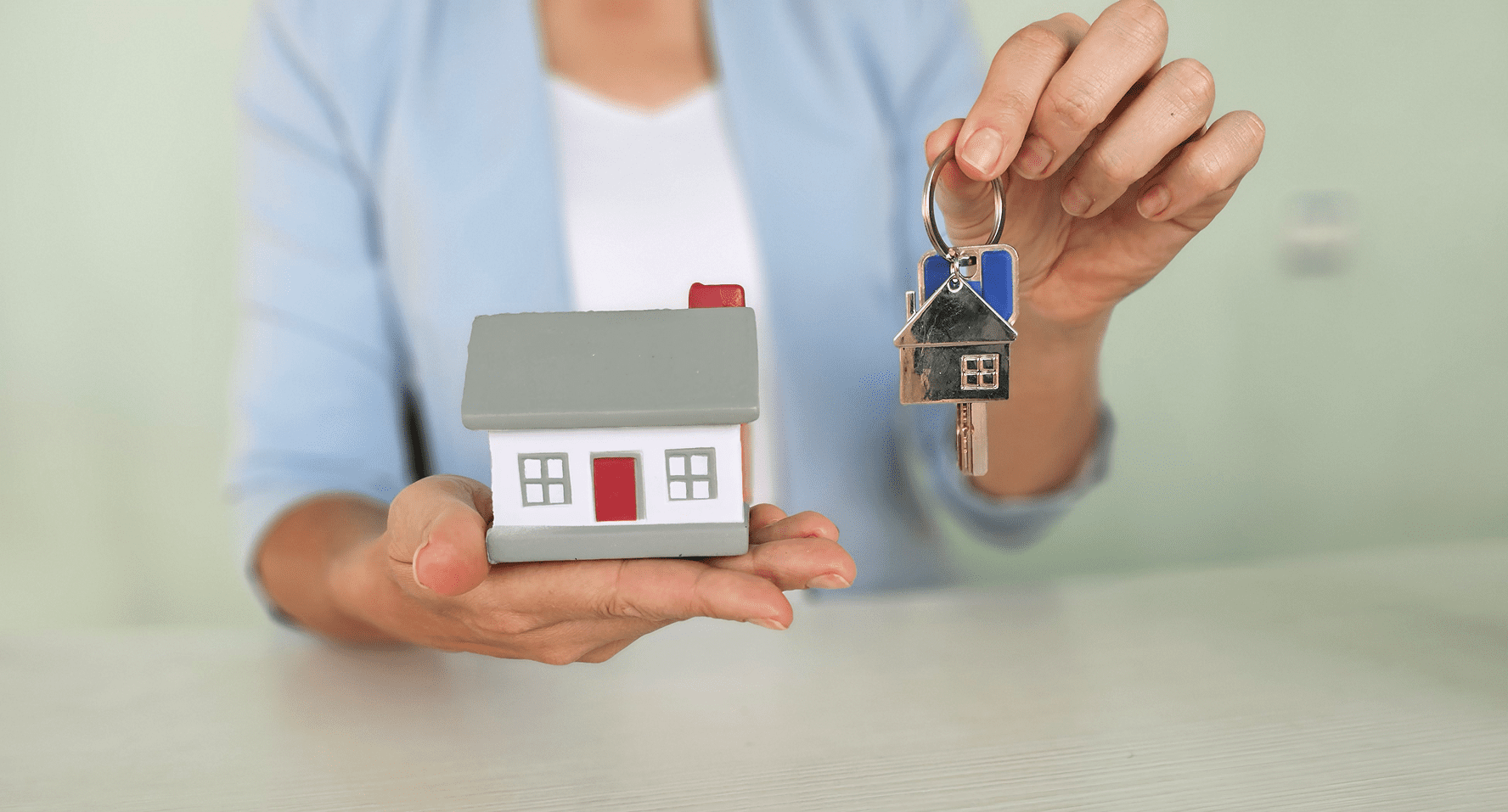 A woman holding a key and a house.